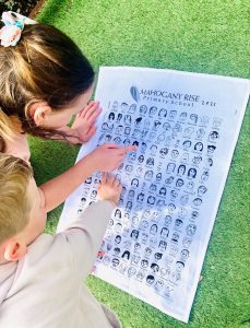 young boy and girl pointing to their drawings on their school's fundraising tea towel